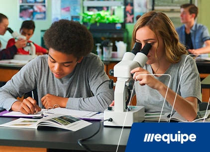 Dois jovens em aula de biologia olhando no microscópio e anotando num caderno - site colégio Equipe Belém - Pará