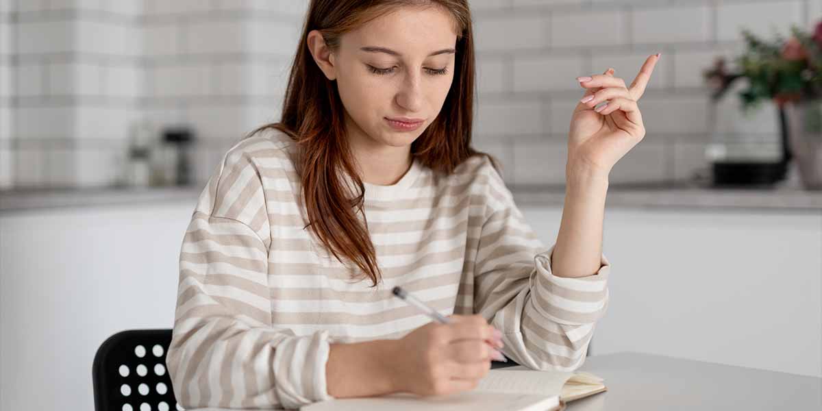 Garota anotando num caderno aprendendo como estudar