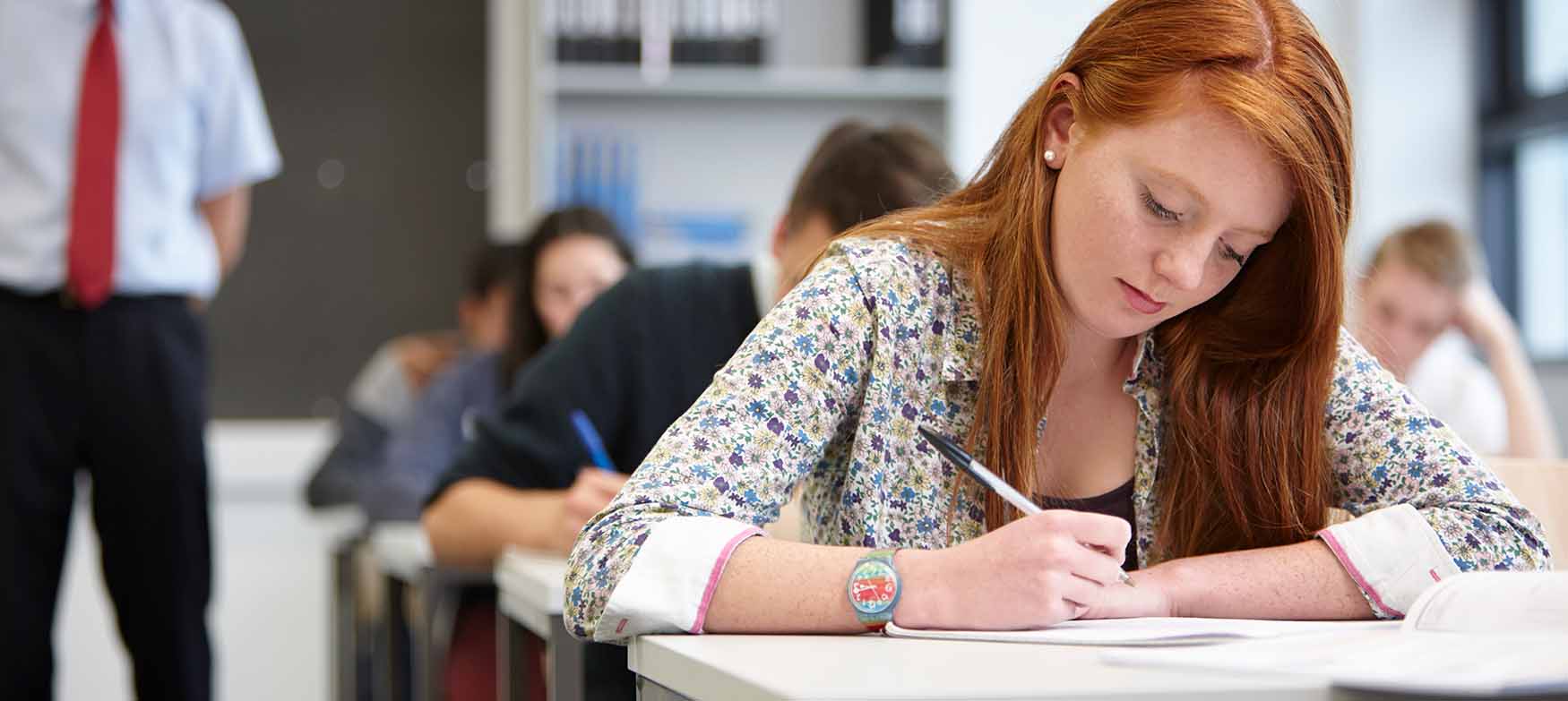 Garota ruiva fazendo uma prova na escola